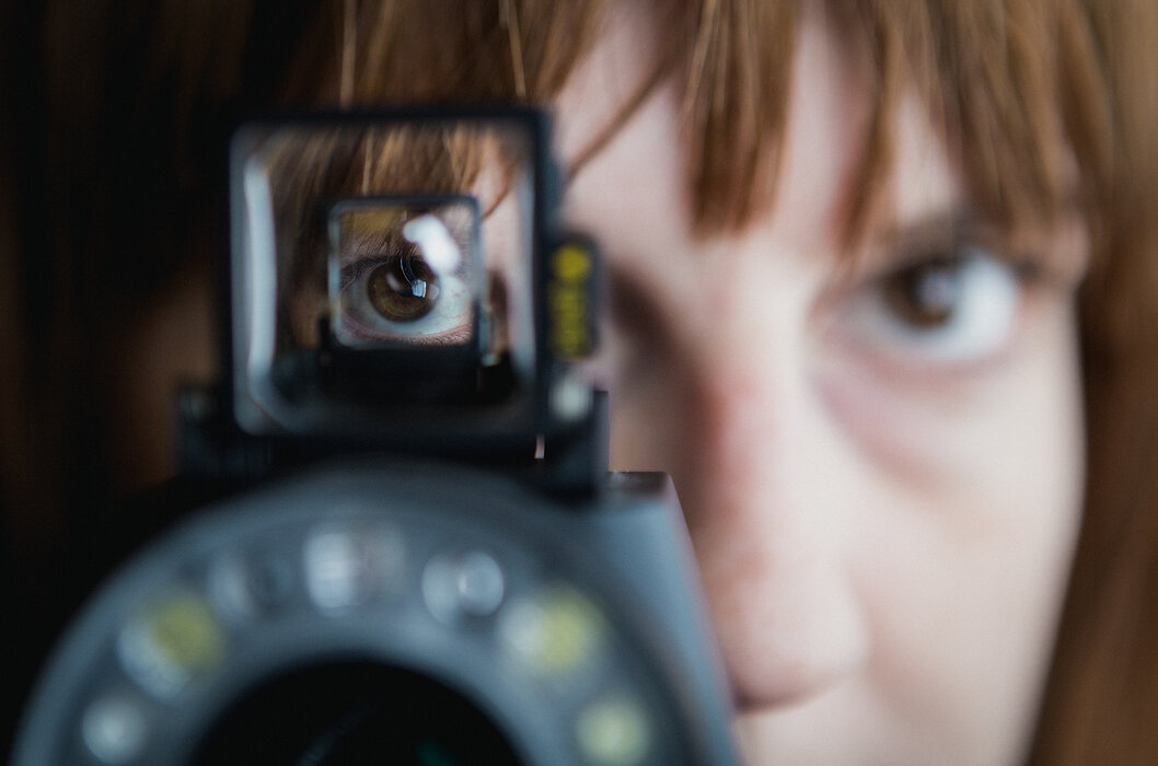 Frau sieht durch den Sucher einer Optik