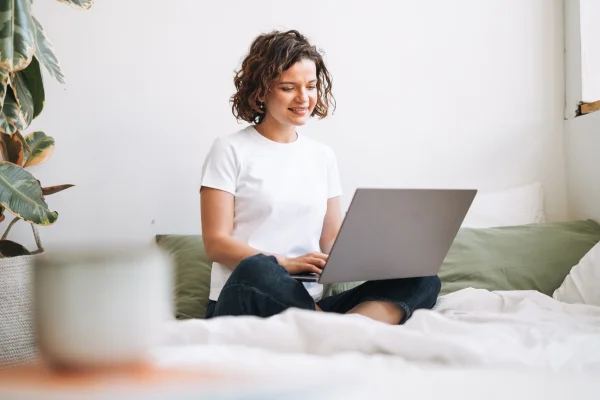 Junge Frau sitzt bequem mit ihrem Laptop auf der Suche nach dem besten Heilpraktiker Tarif